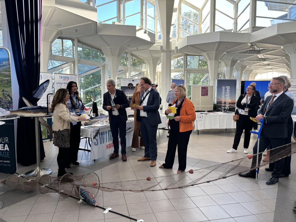 Swimway Expert Group members and ministers from the trilateral countries standing by the Swimway marketplace stall for the ministers event. 